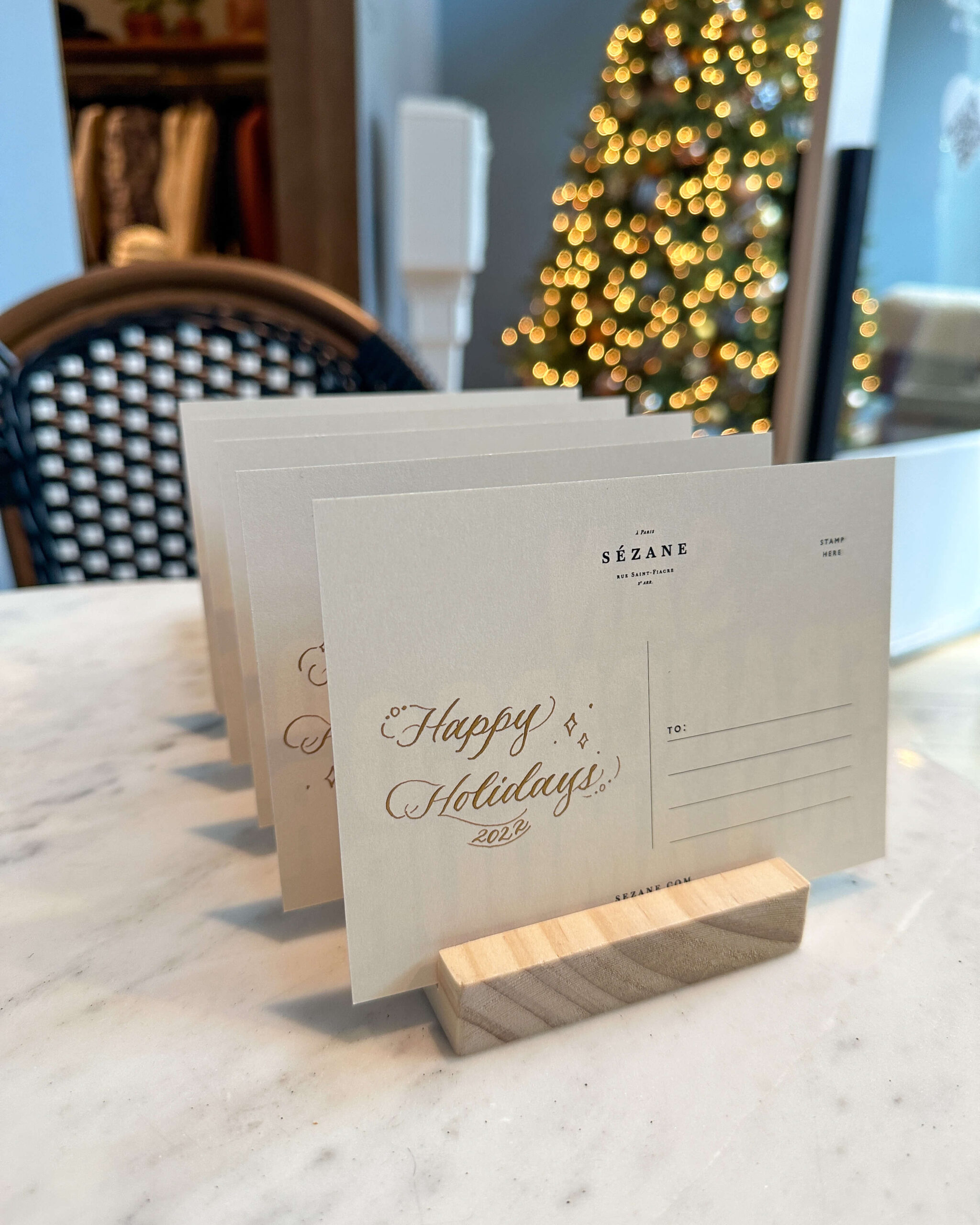 Handwritten calligraphy that says "Happy Holidays" in gold on branded post cards.