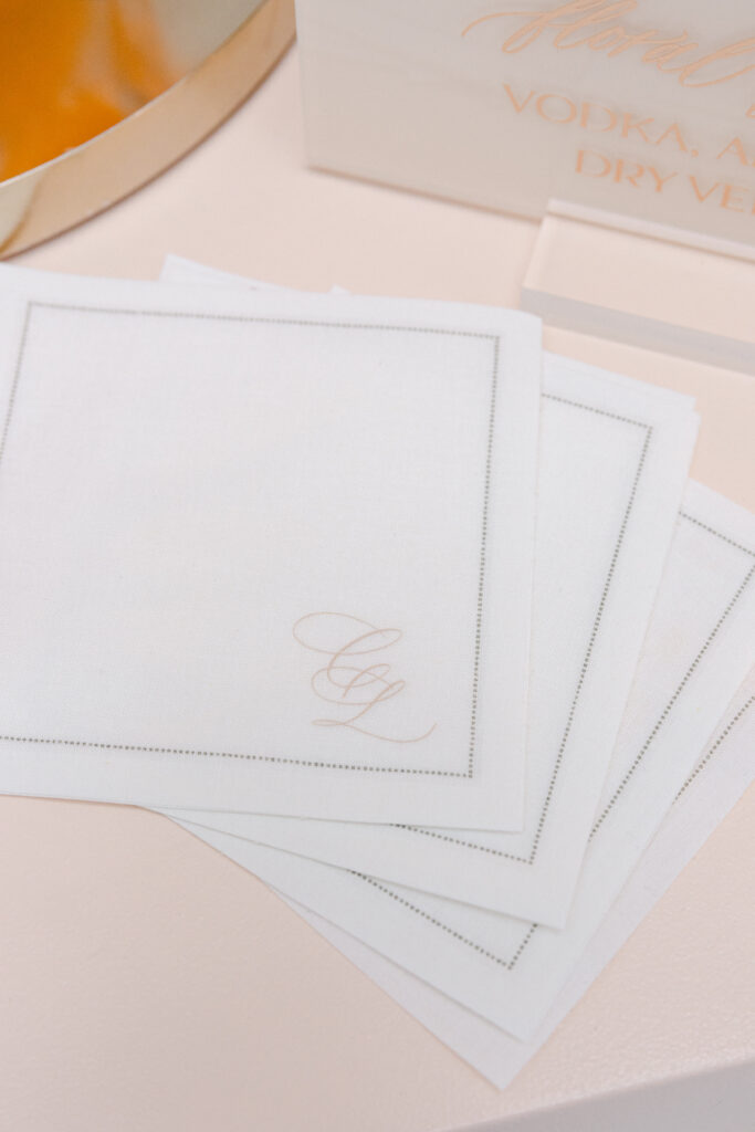 Custom blush calligraphy monogram on white cotton bar napkins.