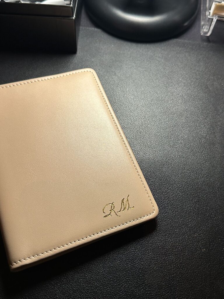 Beige passport cover embossed with gold foiled initials.