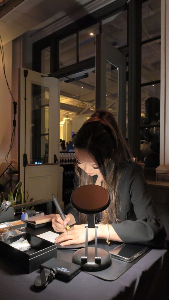 Calligraphy artist embossing initials on leather passports on-site at a company party.