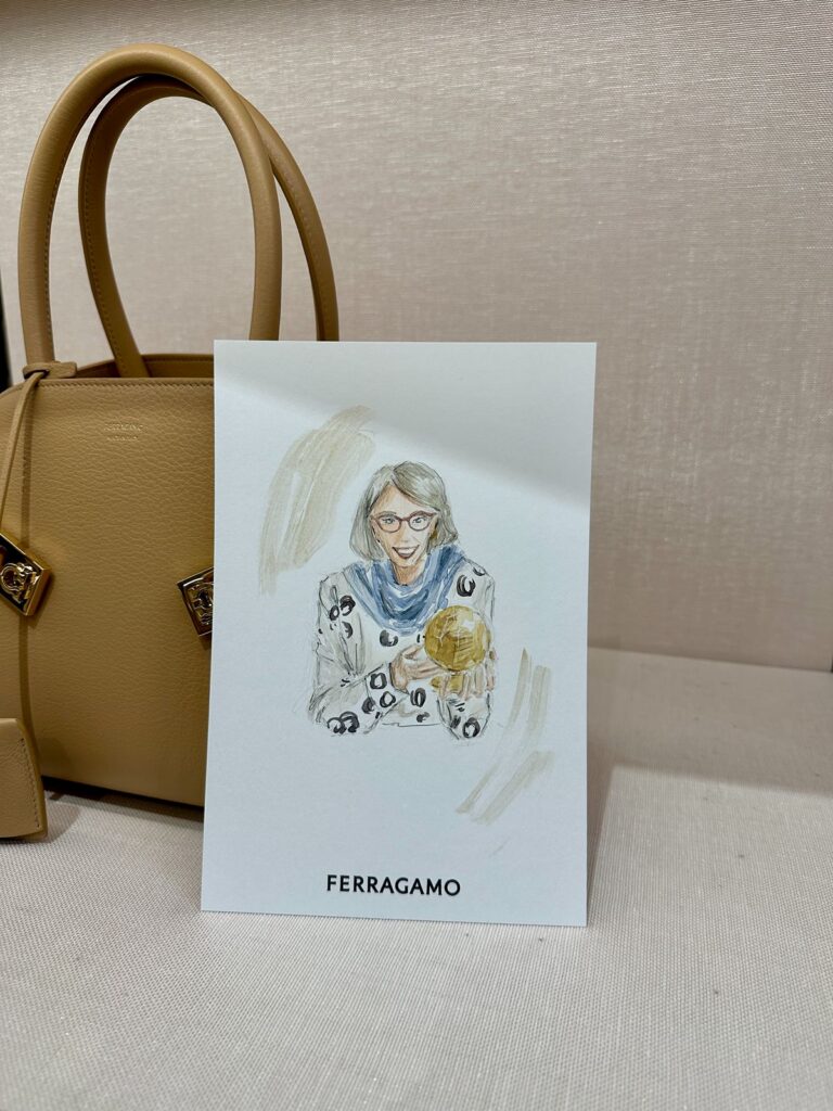 A watercolor portrait of a woman wearing a blue scarf holding a golden snowglobe.