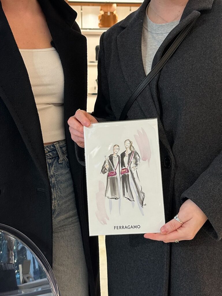 Two friends holding a watercolor illustration of themselves.